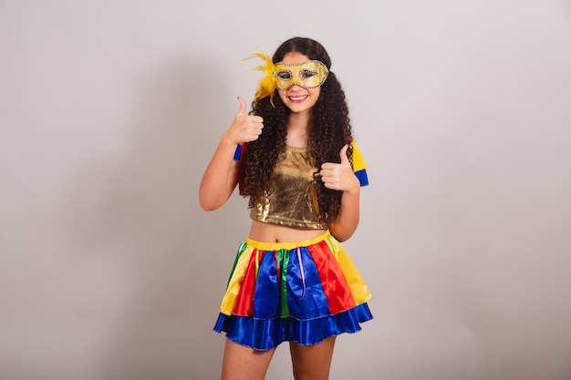 Jovem adolescente brasileira com máscara de carnaval de roupas de frevo como sinal com os dedos