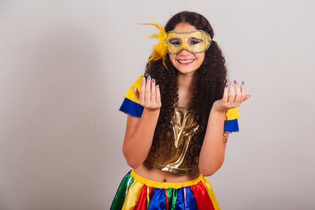 Jovem adolescente brasileira com máscara de carnaval de roupas de frevo convidando com as mãos