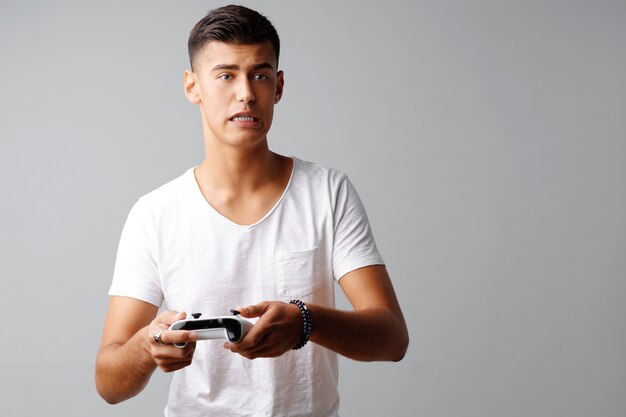 Jovem adolescente brincando com joystick do console sobre um fundo cinza