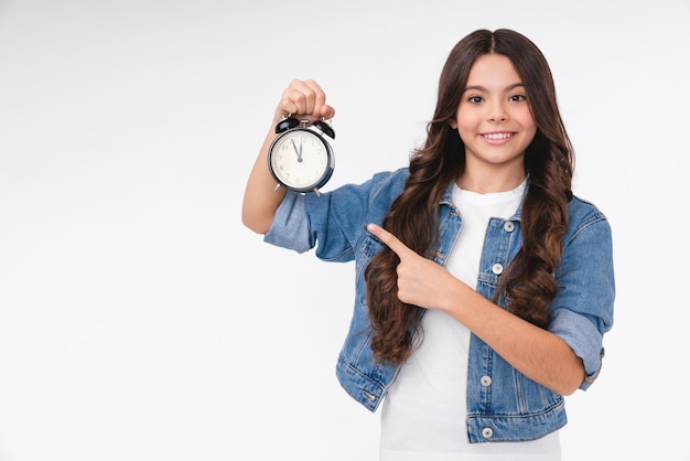 Jovem adolescente caucasiana feliz apontando para o relógio isolado sobre fundo branco