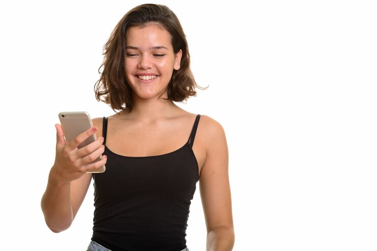Foto jovem adolescente caucasiana feliz sorrindo e segurando um telefone celular