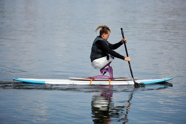 Jovem adolescente com deficiência a fazer paddleboard no lago