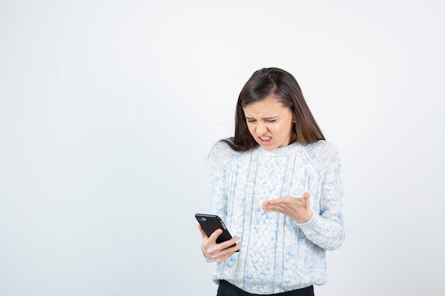 Jovem adolescente segurando o smartphone em fundo branco.