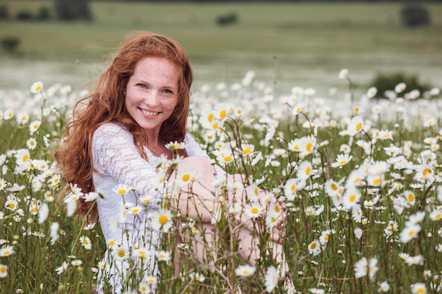 Jovem adorável mulher sorridente maravilha-se na flor, rasgando pétalas