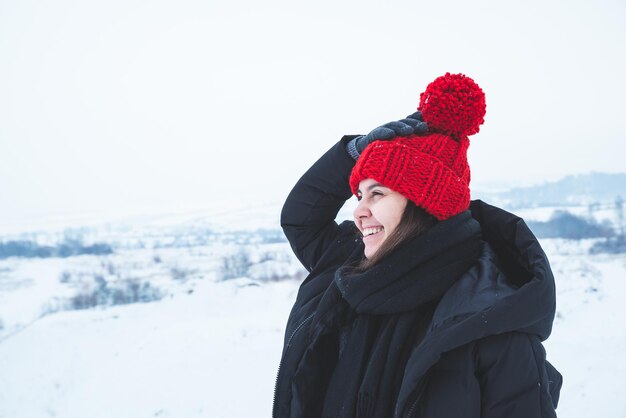 Jovem adulta em roupas de inverno com chapéu vermelho brilhante ao ar livre