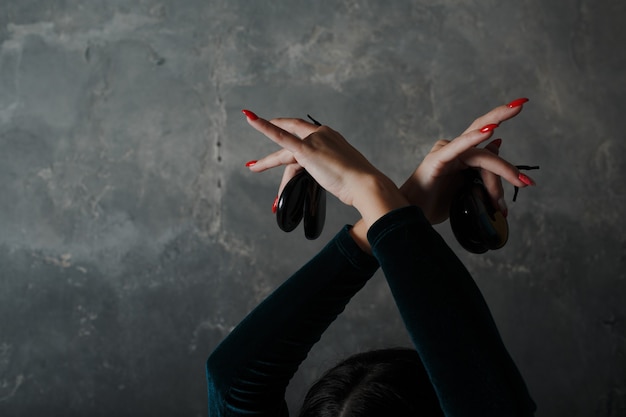 Jovem adulta espanhola dançando flamenco com castanholas em fundo cinza vintage