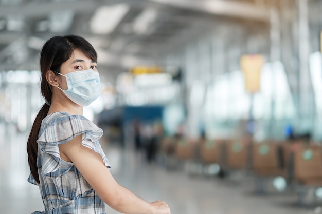 Jovem adulta usando máscara facial em terminal de aeroporto