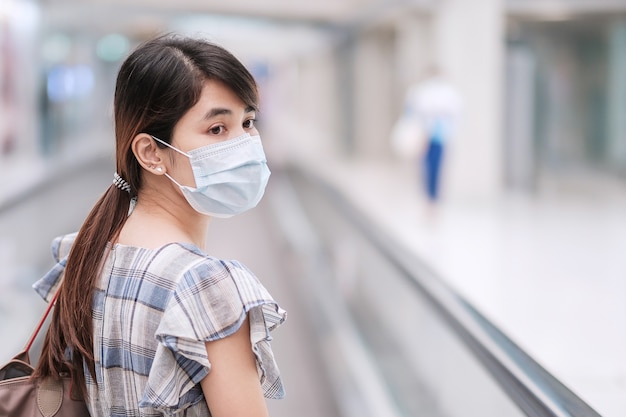 Jovem adulta usando máscara facial em terminal de aeroporto