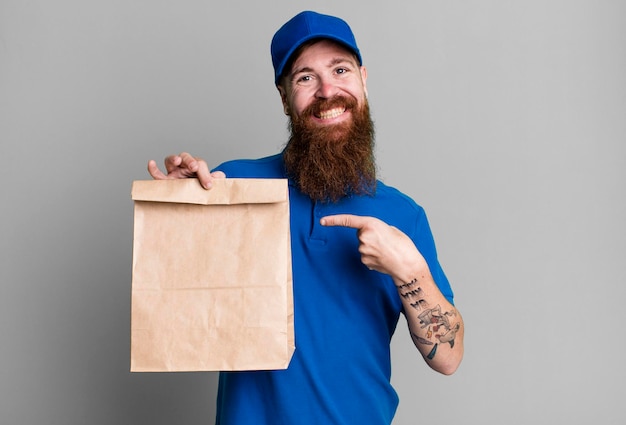 Jovem adulto de cabelo ruivo barbudo entregador legal com um saco de papel