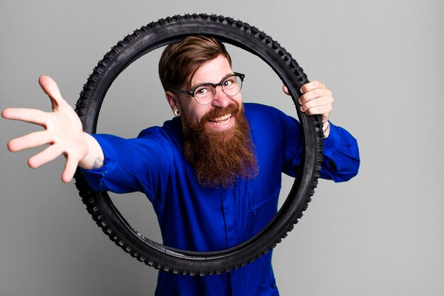 Foto jovem adulto de cabelo ruivo barbudo reparador legal com uma roda de bicicleta