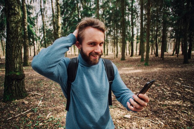 Jovem adulto falando ao telefone em pé na floresta