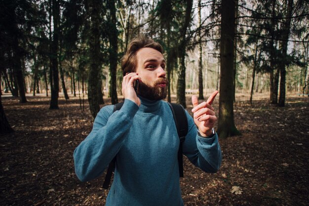 Jovem adulto falando ao telefone em pé na floresta
