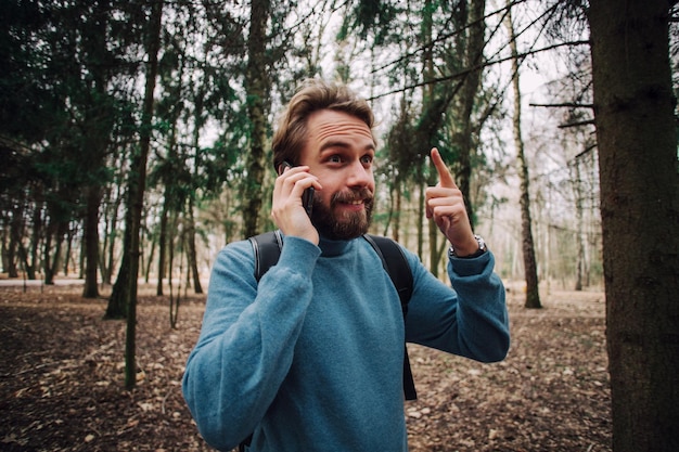 Jovem adulto falando ao telefone em pé na floresta