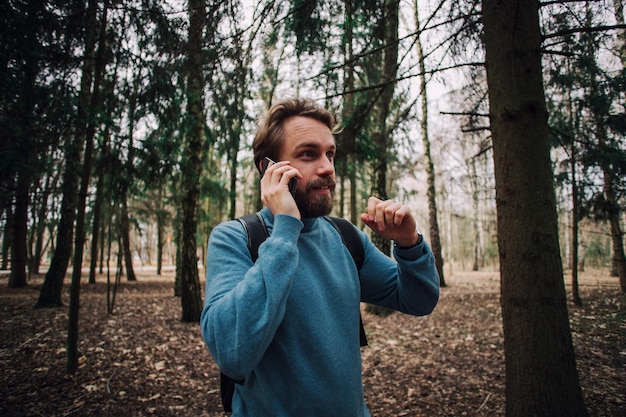 Jovem adulto falando ao telefone em pé na floresta