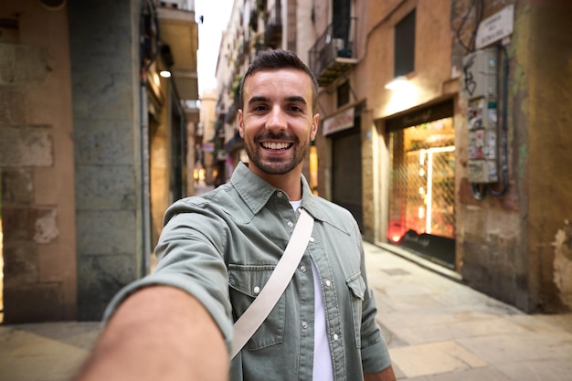 Jovem adulto feliz homem caucasiano tirando selfie sorridente na rua turística da cidade de Madri no fundo