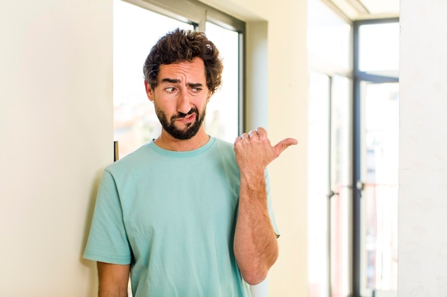 Jovem adulto louco com pose expressiva no interior de uma casa moderna