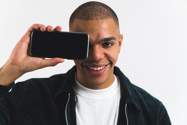 Jovem adulto positivo negro cobrindo seu rosto com um retrato de estúdio de close-up médio por telefone sobre