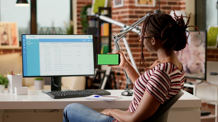 Foto jovem adulto segurando smartphone com tela verde horizontal na mesa de escritório em casa. olhando para o modelo de copyspace em branco com fundo de maquete e exibição de chroma key isolado. tiro de tripé.