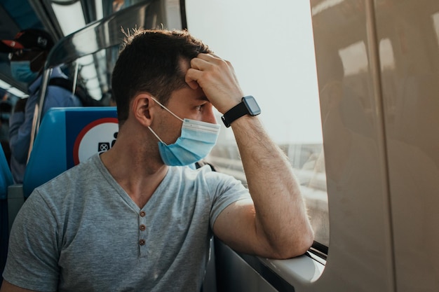 Jovem adulto usando proteção respiratória com máscara de pano no rosto em transporte público