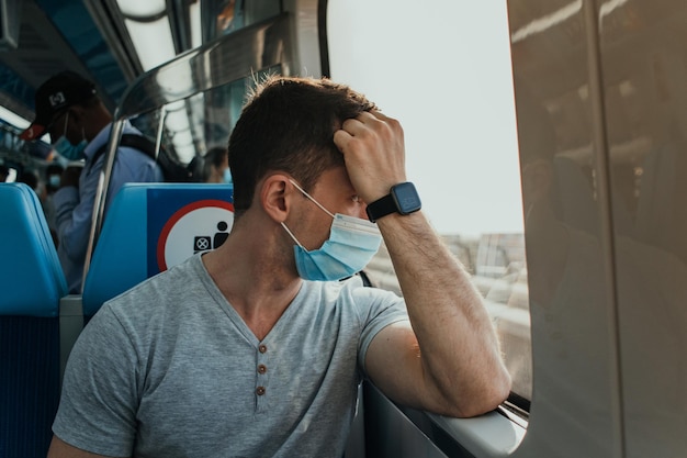 Jovem adulto usando proteção respiratória com máscara de pano no rosto em transporte público