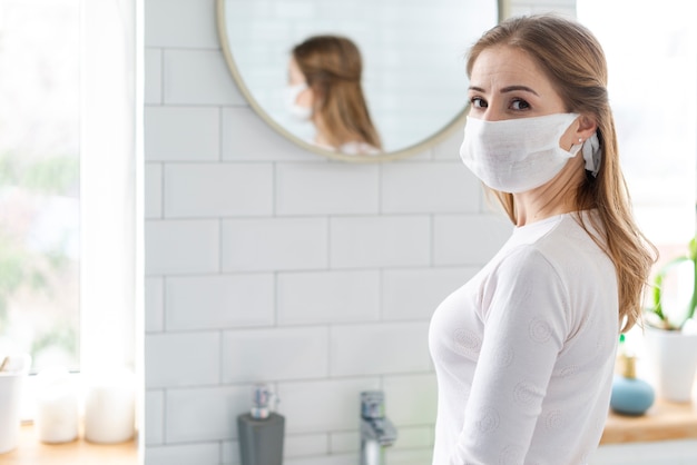 Foto jovem adulto usando uma máscara de proteção no banheiro