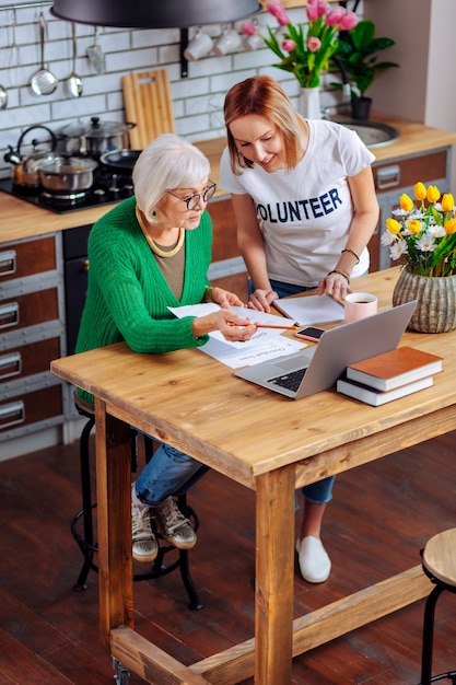 jovem adulto voluntário discutindo com uma mulher idosa na cozinha