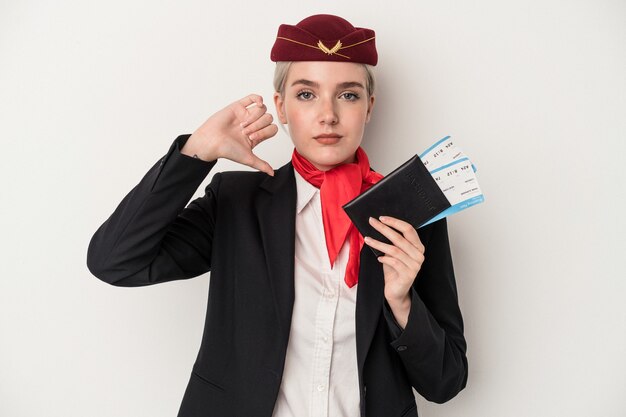 Jovem aeromoça caucasiana mulher segurando passaporte isolado no fundo branco, mostrando um gesto de antipatia, polegares para baixo. Conceito de desacordo.