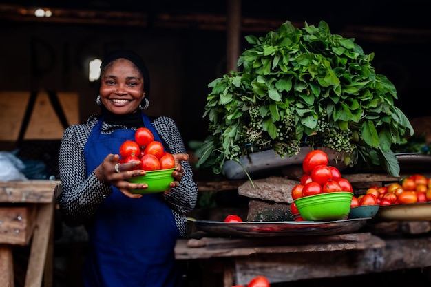 Jovem africana feliz vendendo tomates em um mercado aberto na comunidade