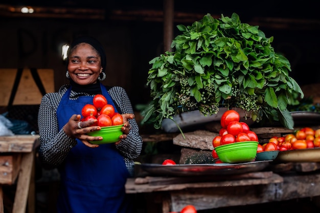 Jovem africana feliz vendendo tomates em um mercado aberto na comunidade