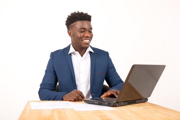 jovem africano bonito à mesa com o laptop