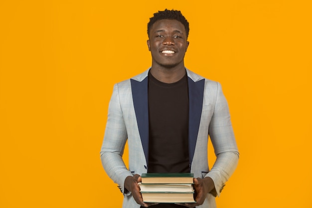 Jovem africano bonito com casaco e livros