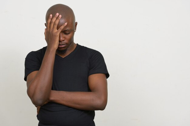 Foto jovem africano careca estressado com dor de cabeça