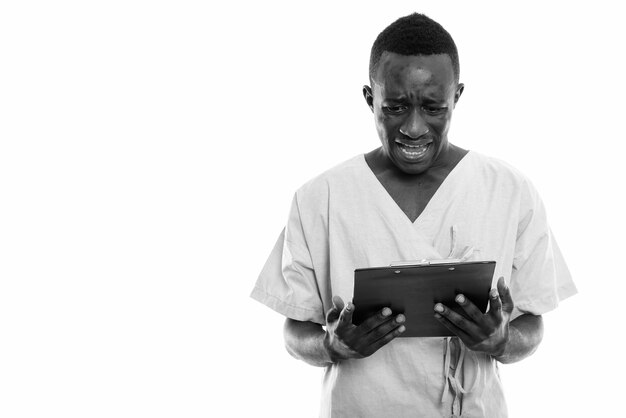 jovem africano como paciente de hospital isolado contra uma parede branca em preto e branco