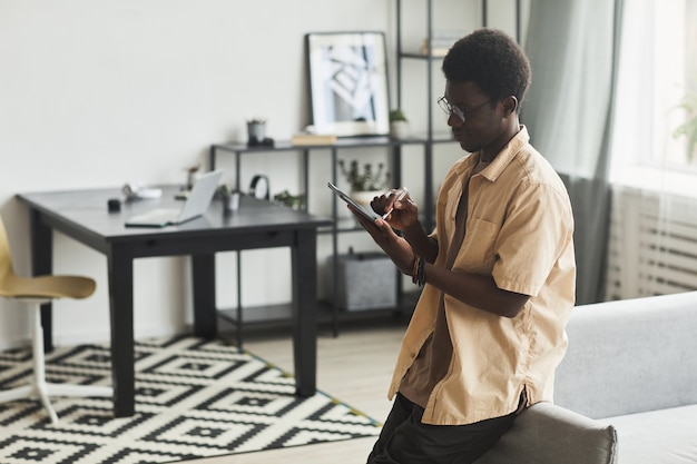 Jovem africano digitando em um tablet digital durante seu trabalho online no escritório