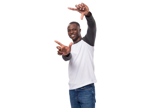 Jovem africano esguio vestido com um moletom preto e branco posando para a câmera