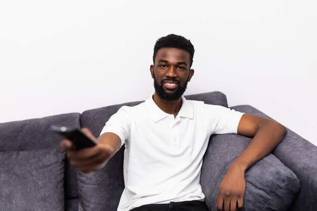 Jovem africano feliz assistindo televisão no sofá de casa