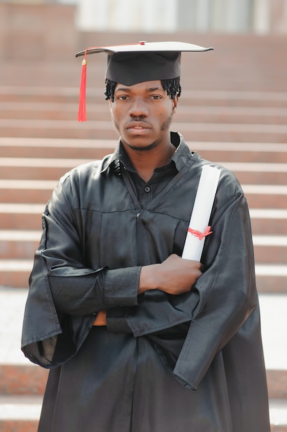 Jovem africano graduado do sexo masculino em frente ao prédio da universidade