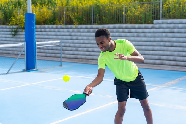 Jovem africano jogando pickleball em uma quadra ao ar livre