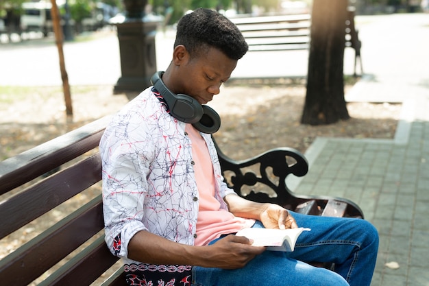 Jovem africano lendo um livro no parque