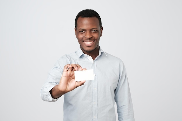 Jovem africano segurando o cartão de visita do banco em fundo cinza