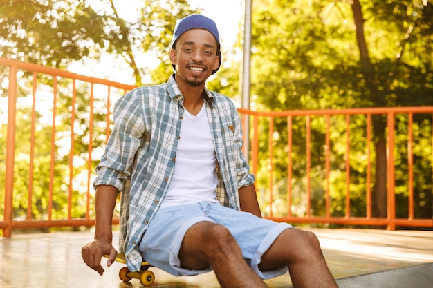 Jovem africano sorridente com skate