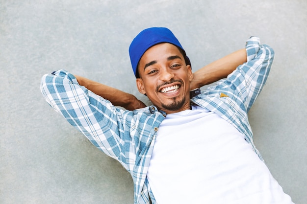 Jovem africano sorridente deitado em um concreto