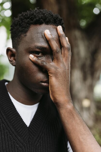 Jovem africano triste com gesto de facepalm olhando por entre os dedos