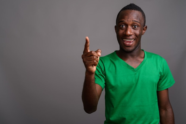 Jovem africano, vestindo camisa verde na parede cinza