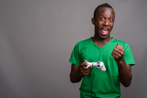 Jovem Africano, vestindo camisa verde na parede cinza