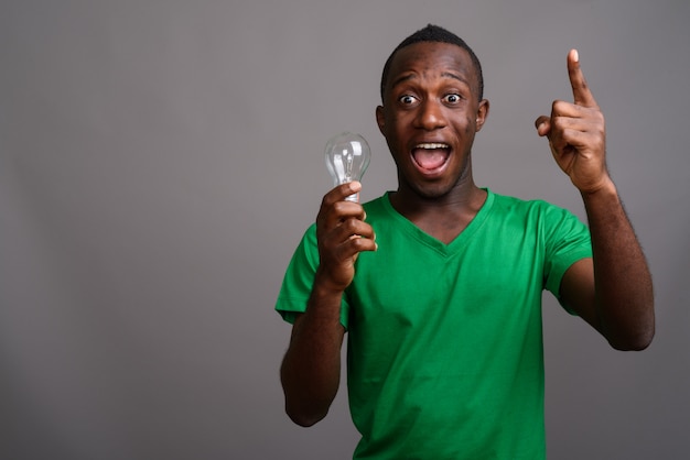 Jovem africano, vestindo camisa verde na parede cinza