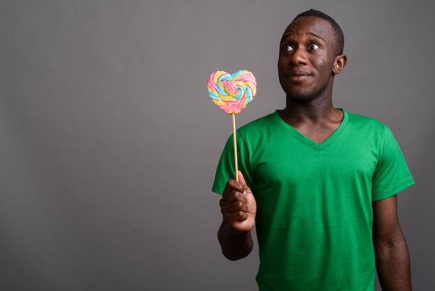 Jovem Africano, vestindo camisa verde na parede cinza