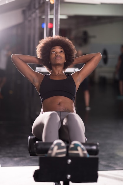 jovem afro-americana apta a fazer abdominais no estúdio de fitness no ginásio.
