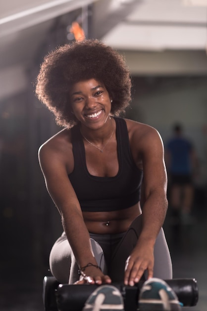 jovem afro-americana apta a fazer abdominais no estúdio de fitness no ginásio.