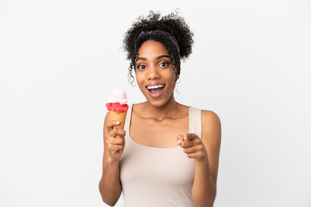 Jovem afro-americana com um sorvete de corneta isolado no fundo branco surpresa e apontando para a frente